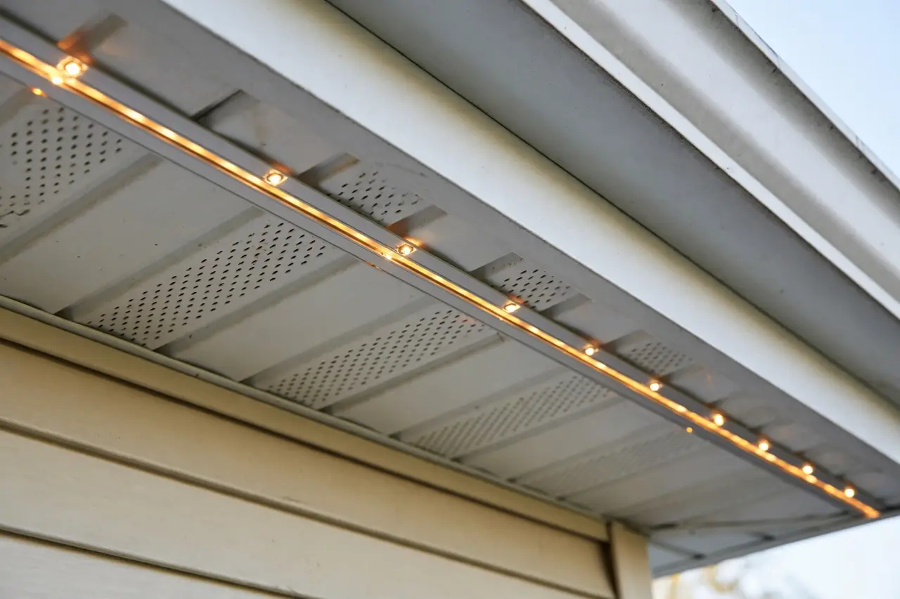 Close view of a slim permanent light track tucked under a home's eave, nearly invisible in daylight